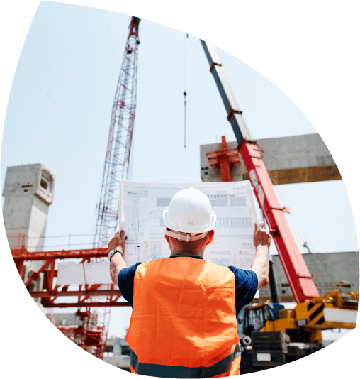 A professional builder holding a blueprint with ongoing construction in the background, highlighting the importance of a builders insurance quote from Be Covered Insurance for comprehensive coverage including indemnity and liability insurance.